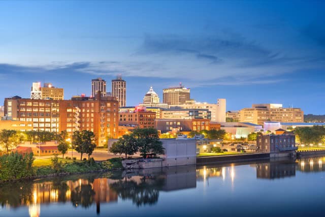 The downtown skyline of Peoria, Illinois, is beautifully reflected on the lake at dusk.