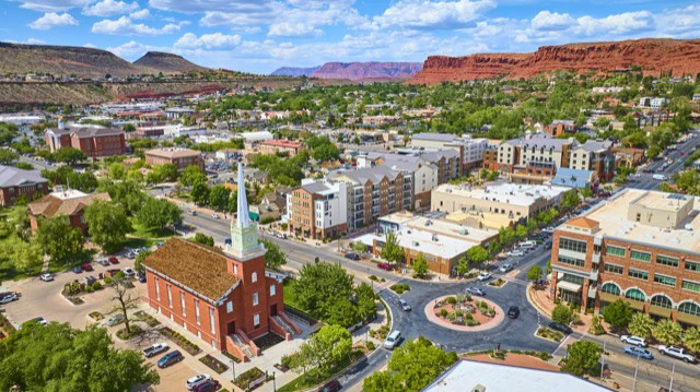 Aerial view of downtown St George with a historic red brick church and clock tower.